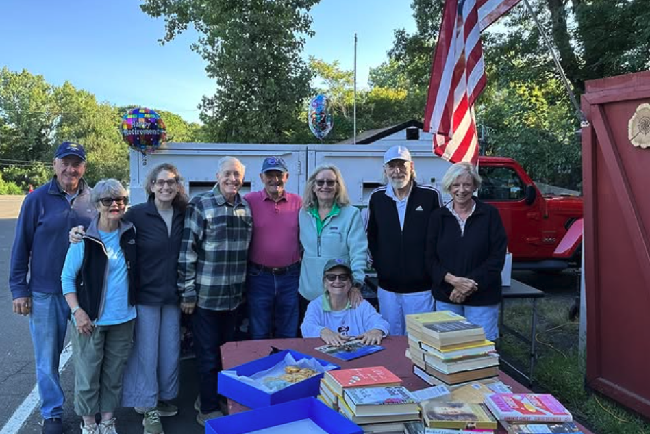 People gather in front of book swap table to pose for photo.