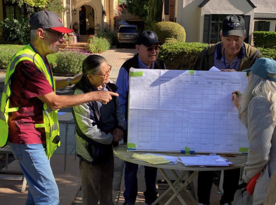 Burlingame volunteers stand around a table reviewing a large incident-tracking board during a neighborhood disaster response drill.