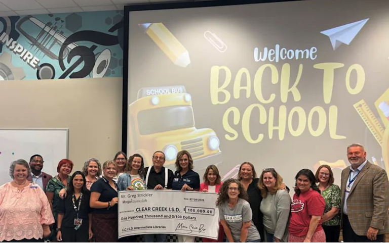 Group gathers in front of back to school sign to celebrate check donation for libraries in the district,