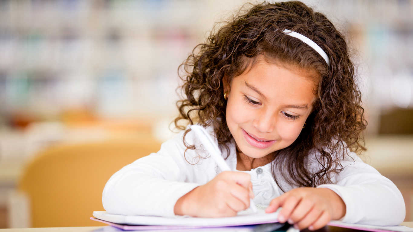 Girl studying and writing in notebook for learning.