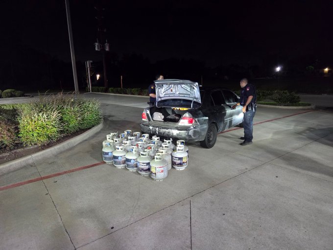 Police investigate a vehicle after numerous propane tanks were found outside the car at night.