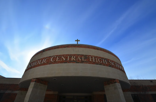 Exterior entrance of Detroit Catholic Central High School in Novi, with the school name displayed above the doorway beneath a cross.