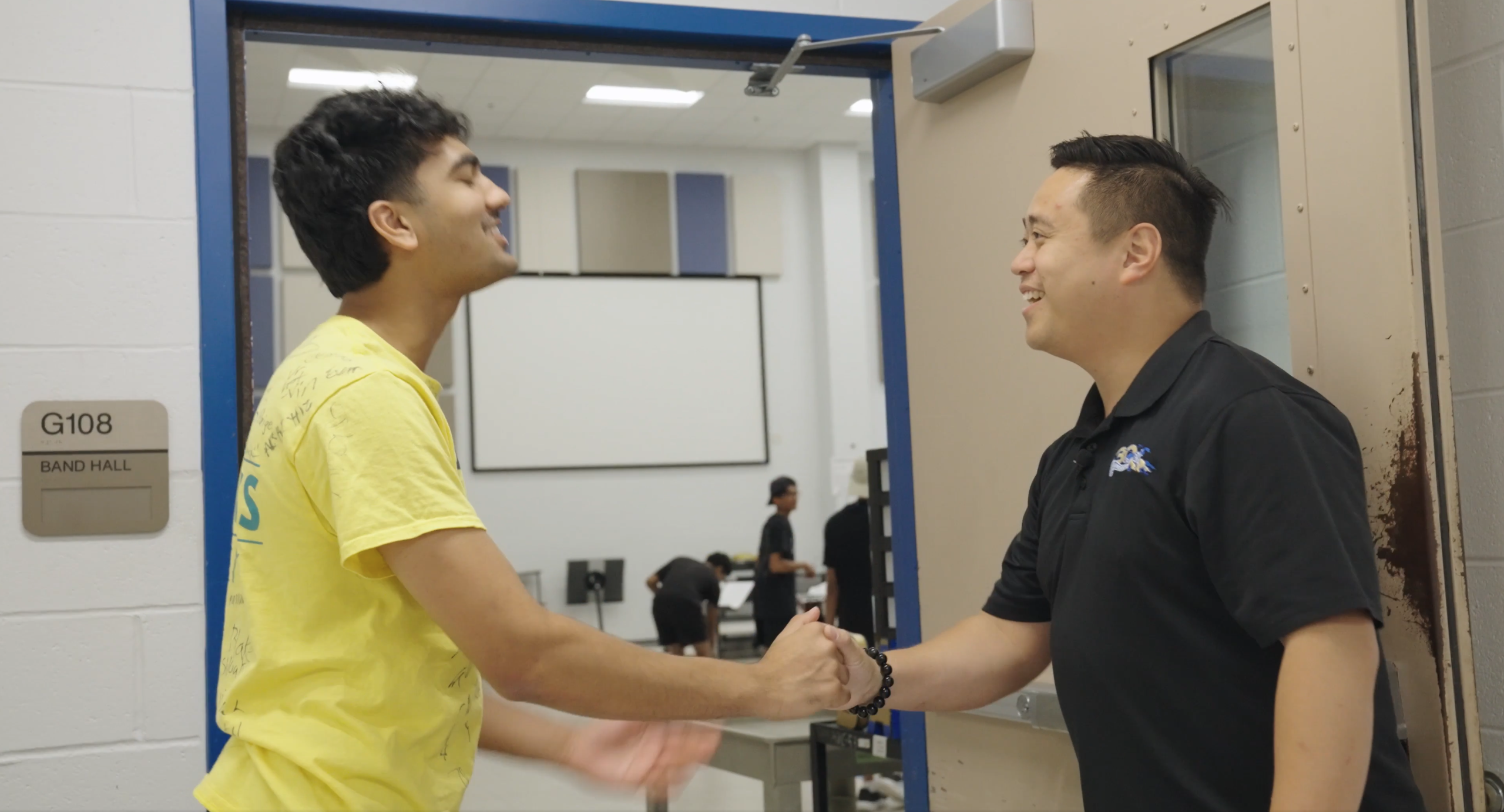 Teacher and student shaking hands outside band room at Elkins High School in Texas.