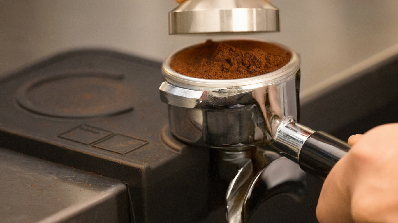 Espresso coffee grinds being pressed near coffee maker.