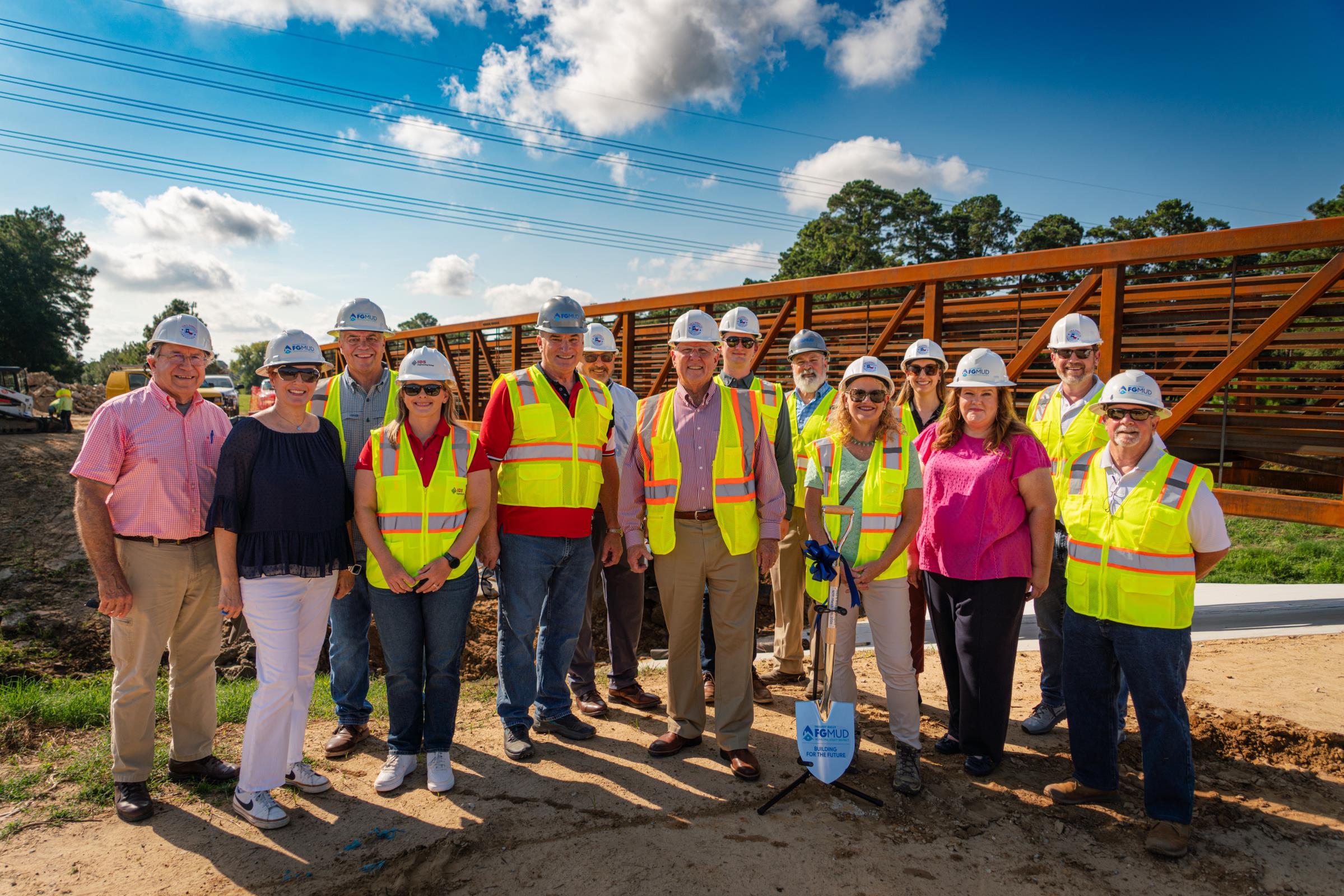 Group of people gather to break ground for new trail dedication ceremony.