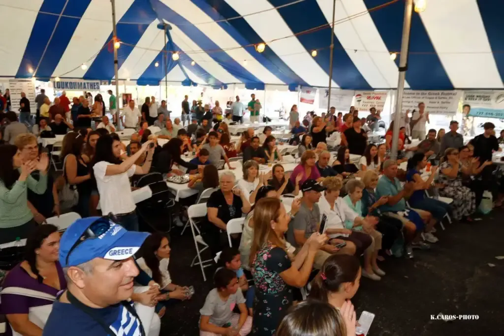 Festivalgoers gather beneath a blue-and-white striped tent at a past Clearwater GreekFest.