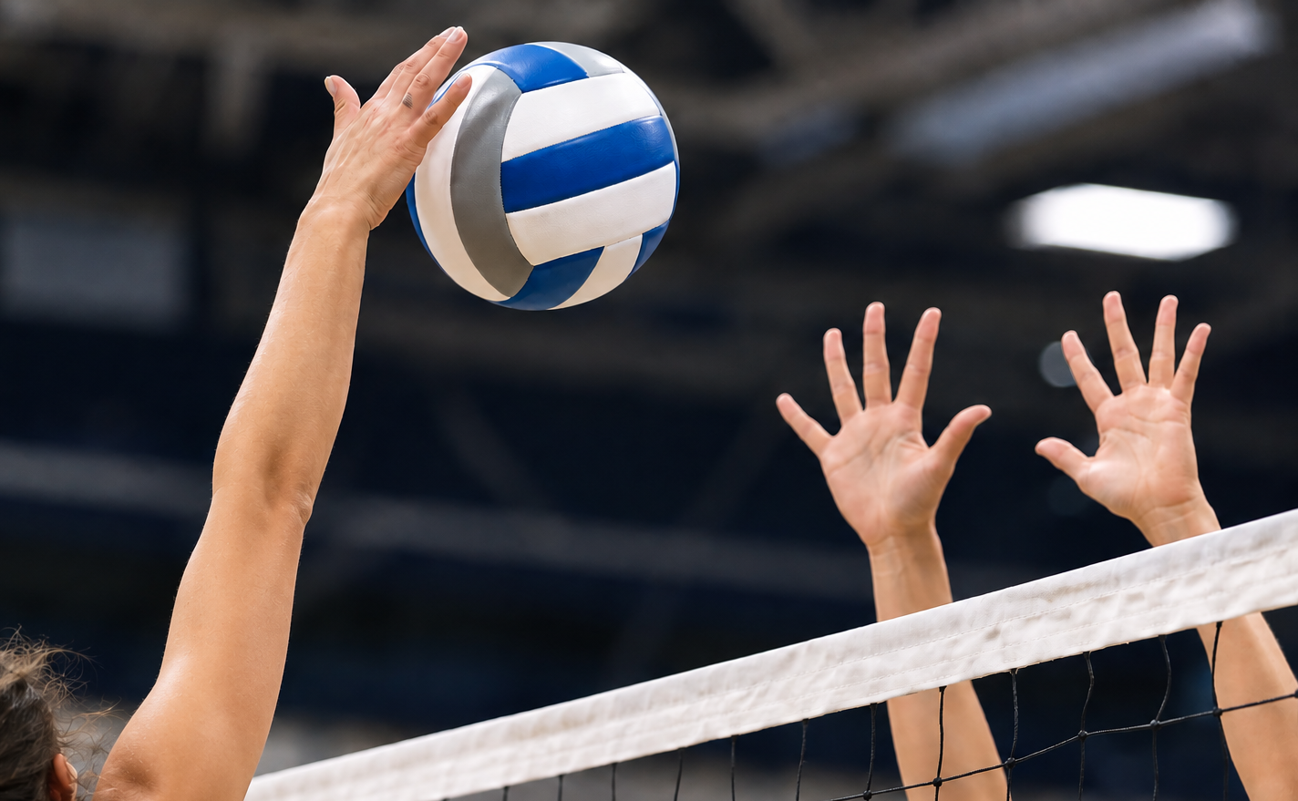 Two people at volleyball net where one person is spiking.