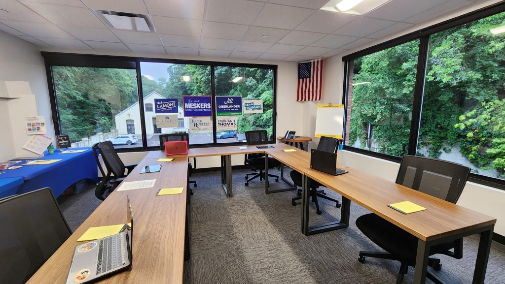 Empty office with brown u-shaped desk and black chairs.