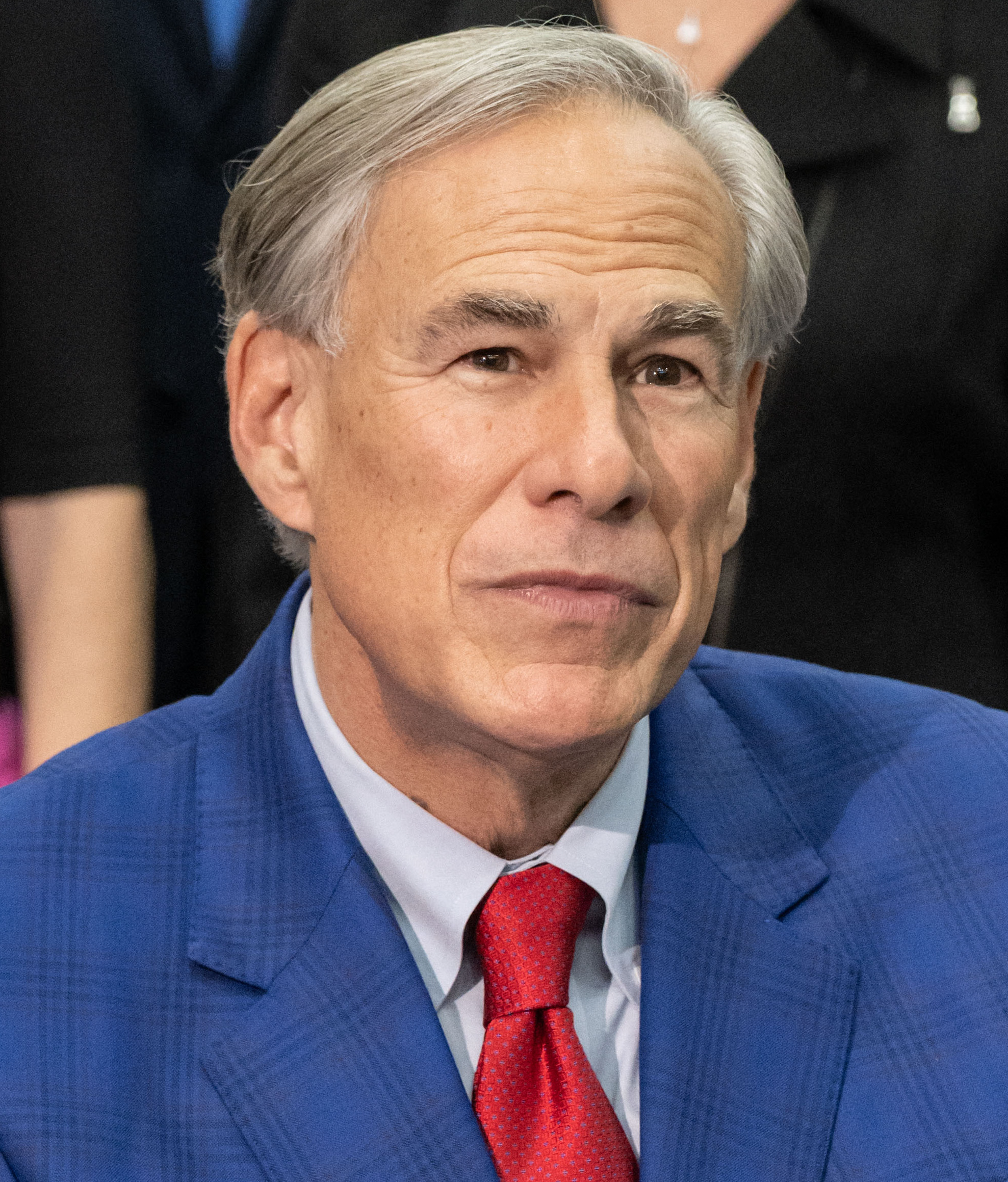 Texas Gov. Greg Abbott wearing a blue suit and red tie.