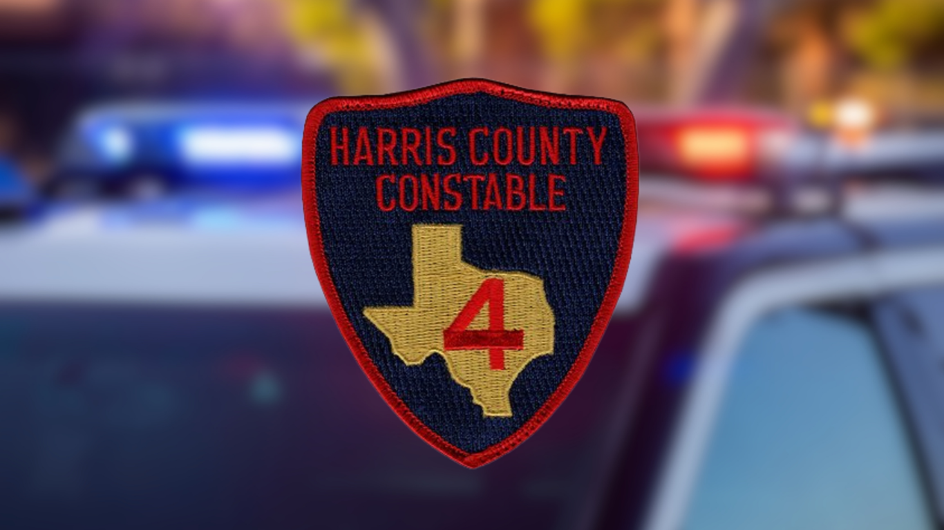 A shield-shaped patch reading "Harris County Constable" with a gold Texas state outline and a red number "4," set against a blurred background of a police vehicle with its blue and red lights on.