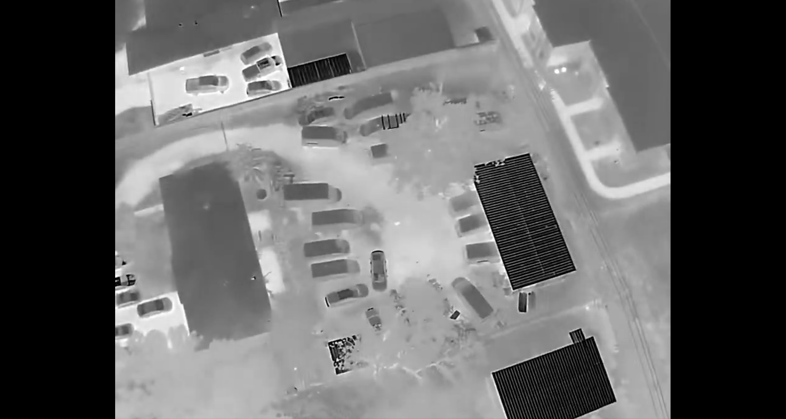 Drone video in black and white of buildings and cars.
