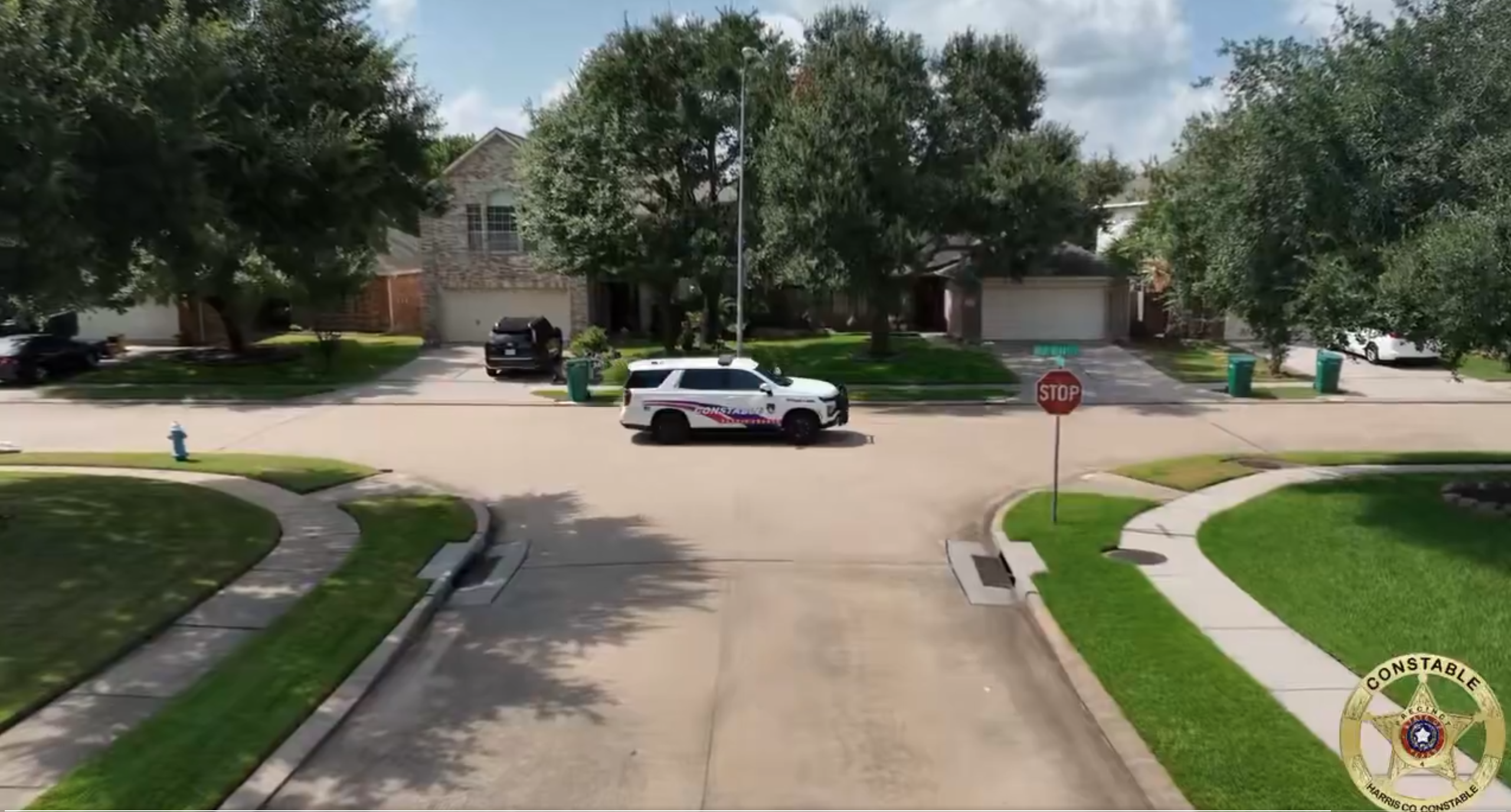 A cop car driving through a neighborhood.