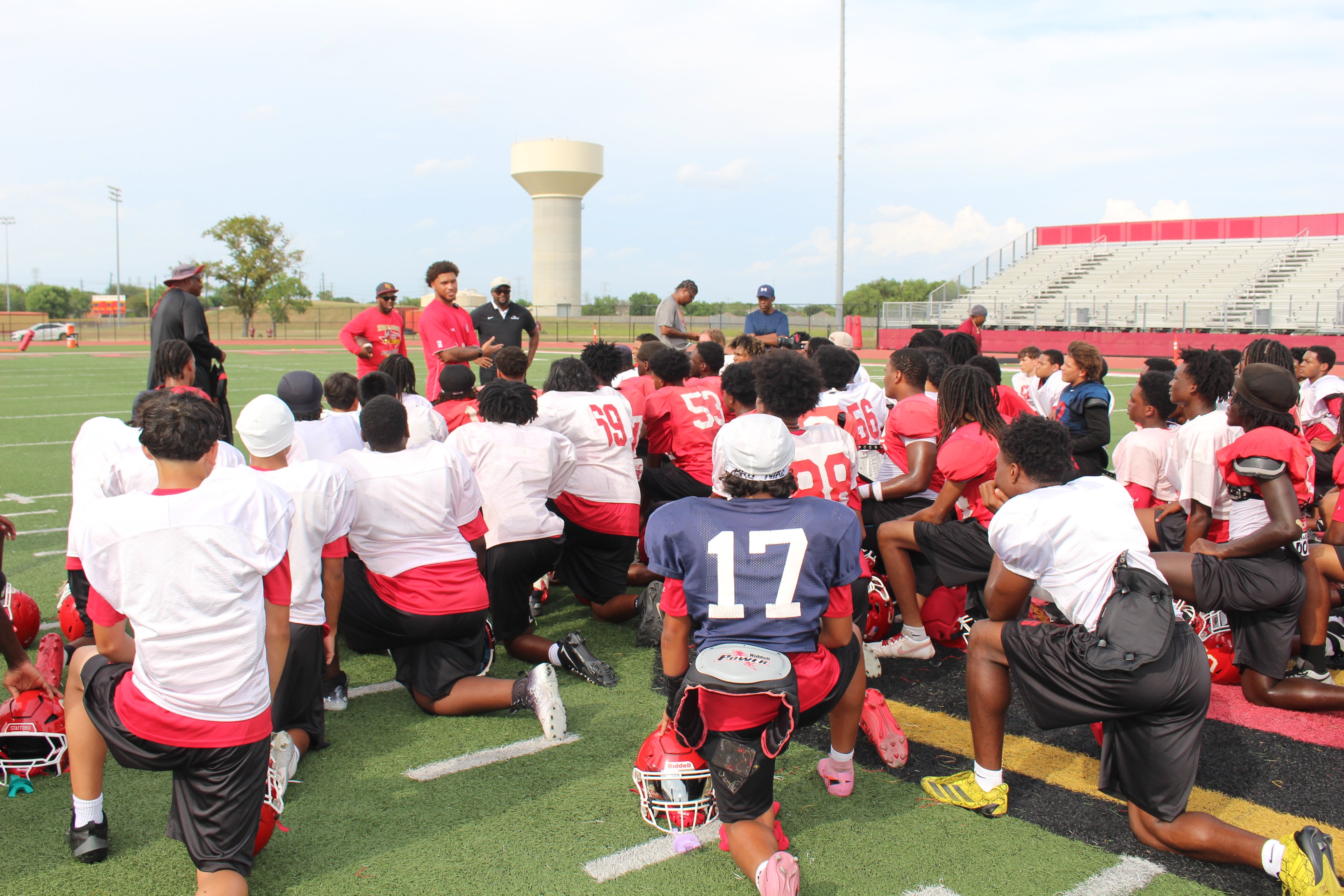 Football team gathers to listen to NFL player and coaches