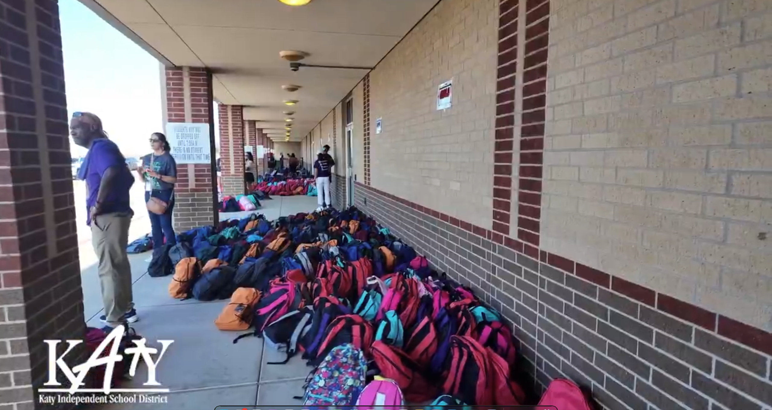 Backpacks lined up for school giveaway at local building.