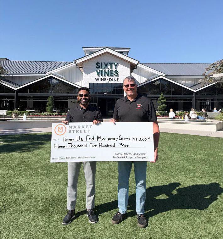 Two men hold an oversized $11,500 check from Market Street to Keep Us Fed Montgomery County outside Sixty Vines.