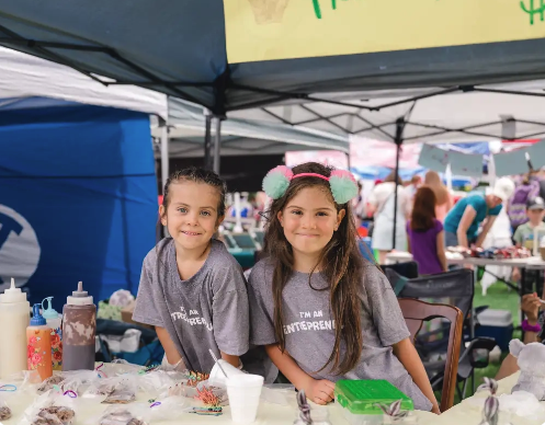 Two girls vendor their own shop at kids market.
