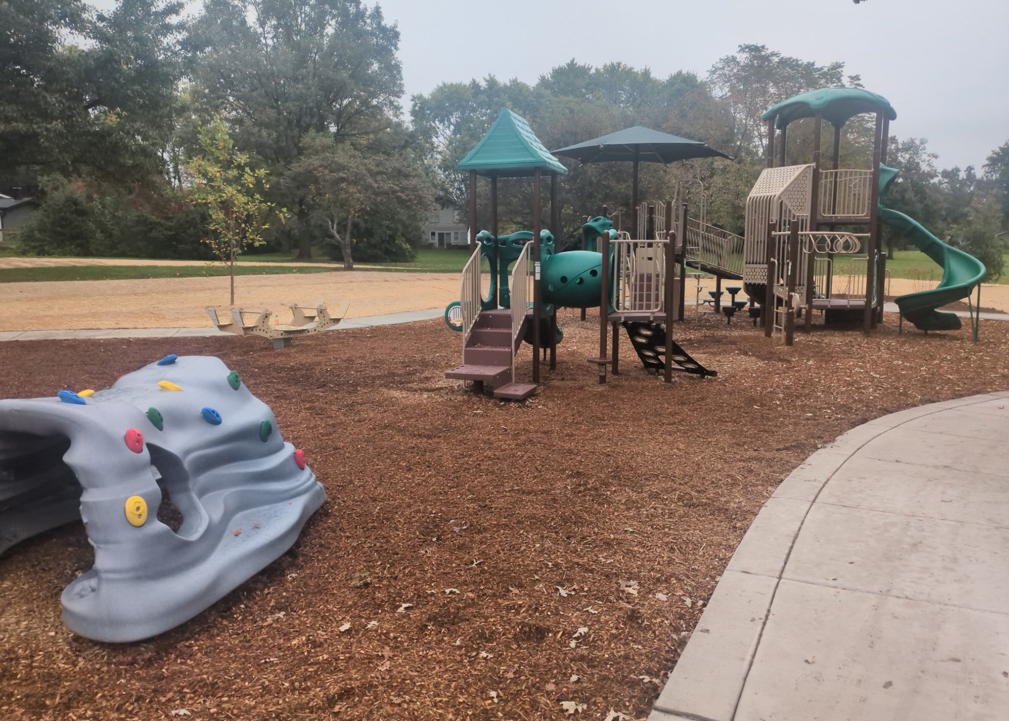 Playground with slides and rock climbing at local park on a gray day.