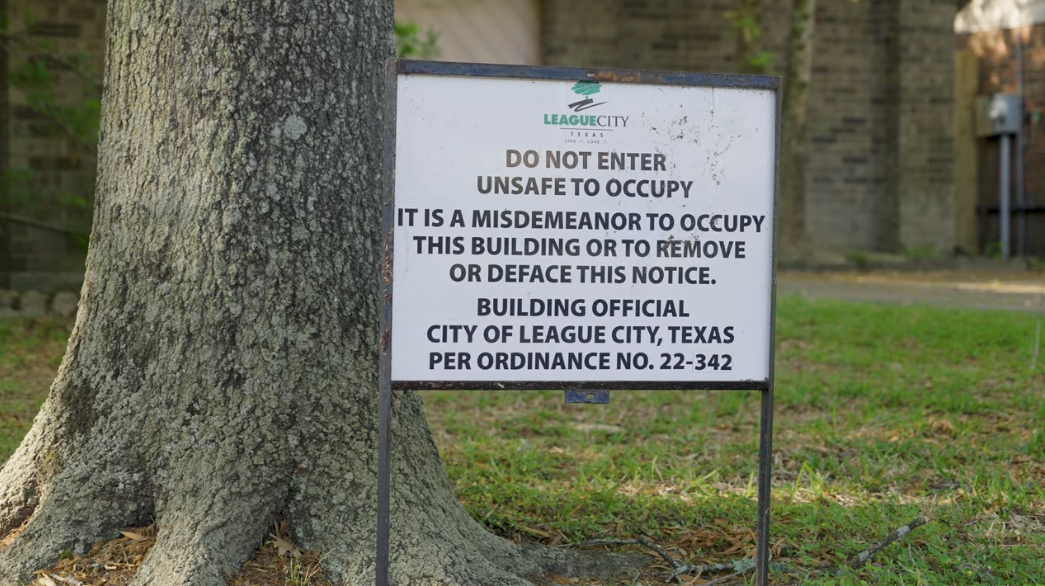 An official League City sign warning that a building is unsafe to occupy, posted on the property under city ordinance.