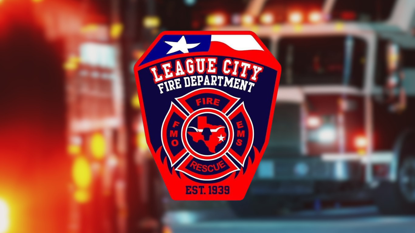 Red, navy, and white League City Fire Department badge with a Texas flag corner, a maltese cross centered on a Texas outline, and "Est. 1939," over a blurred nighttime fire truck background.