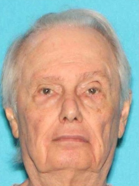 Man poses for photo in front of blue background.
