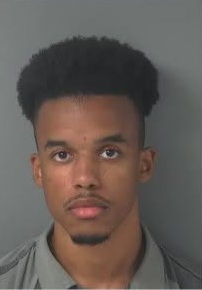 Man in front of gray wall stands for mug shot photo.