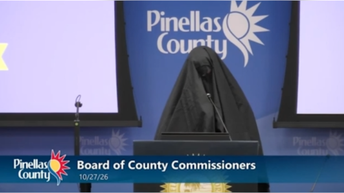 A woman in a black niqab stands at the podium during the Oct. 27 Pinellas County Commission meeting, with the county seal behind her.