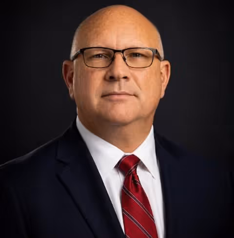 Man in suit wearing red tie smiling for photo.