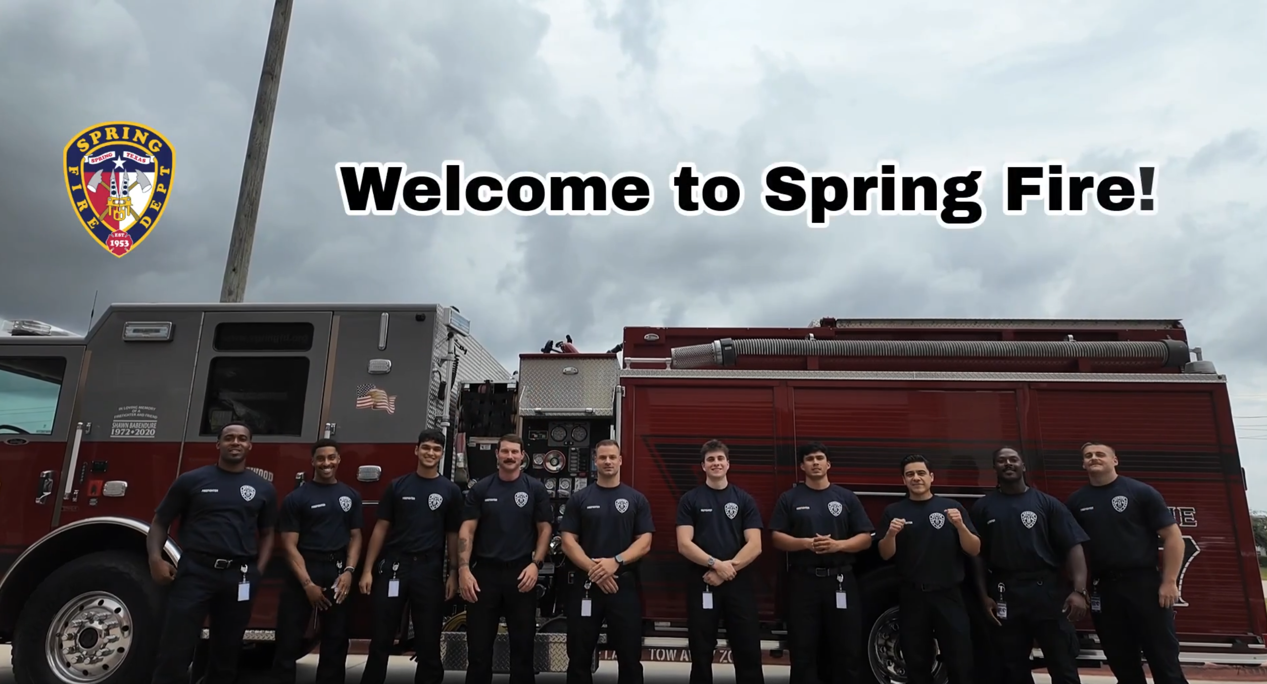 Ten firefighters standing near big red fire truck.