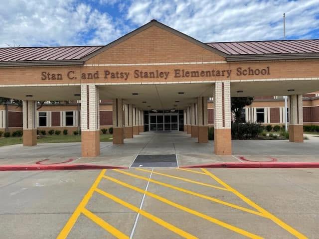 The covered entrance to Stan C. and Patsy Stanley Elementary School, with brick columns and yellow pavement markings in front.