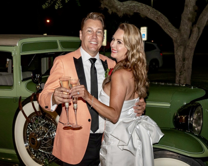Man in suit and woman in white wedding dress holding glasses of champagne.