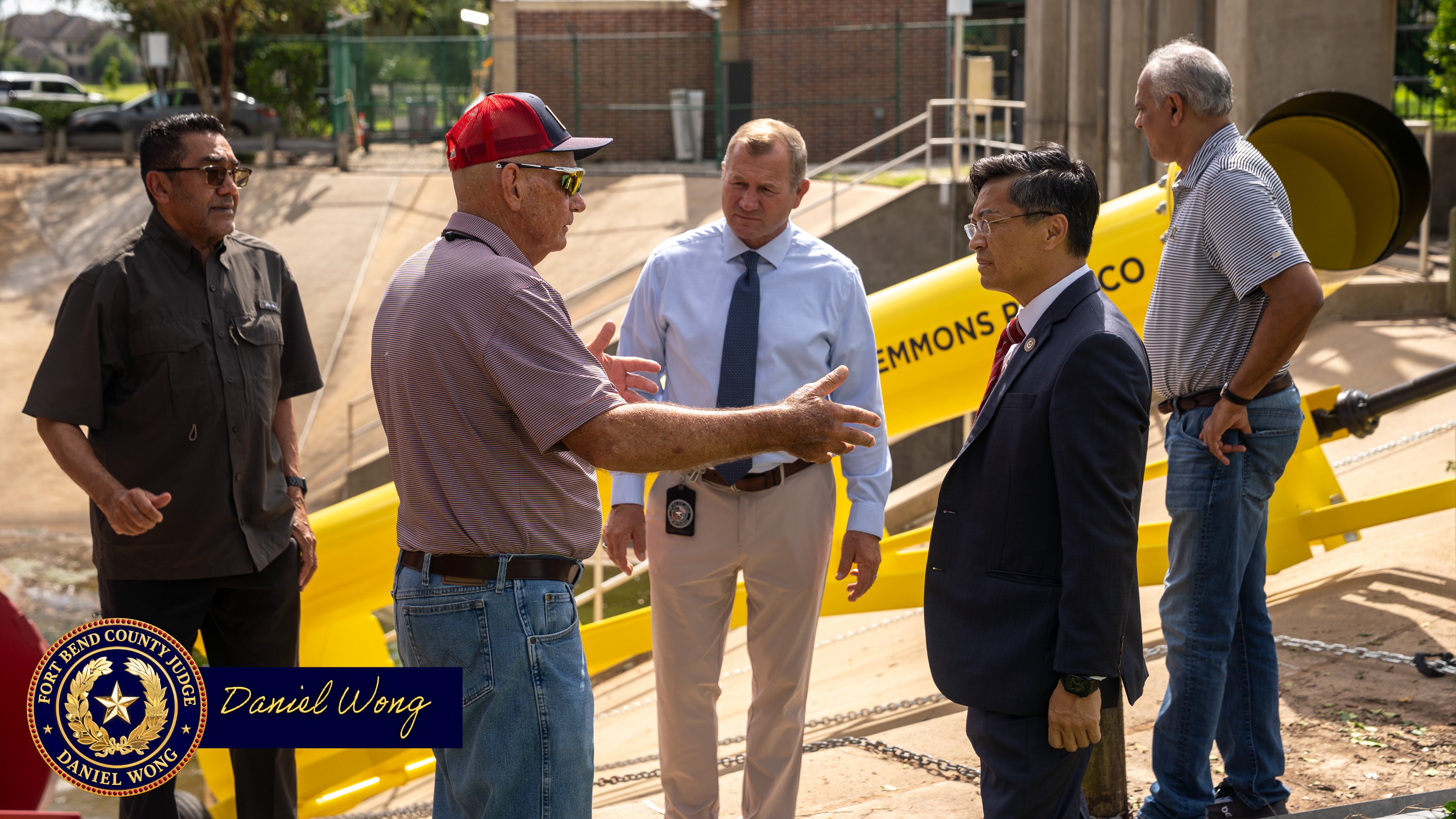 Five men talk near a yellow playground slide at a park. A graphic in the lower-left corner identifies Daniel Wong.