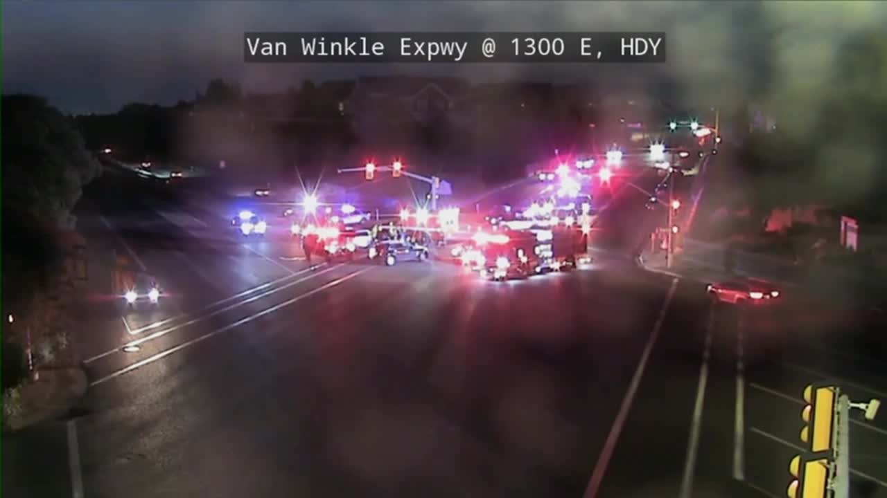 Emergency vehicles with flashing lights blocking an expressway at night.