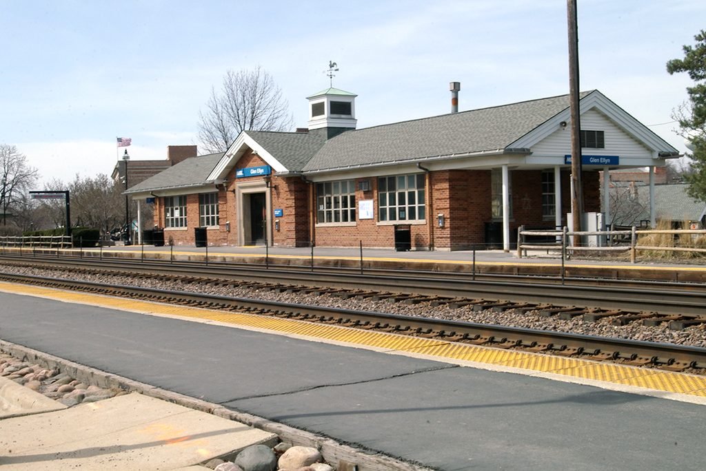 Brick Metra station building with platform, tracks, and yellow safety strips.