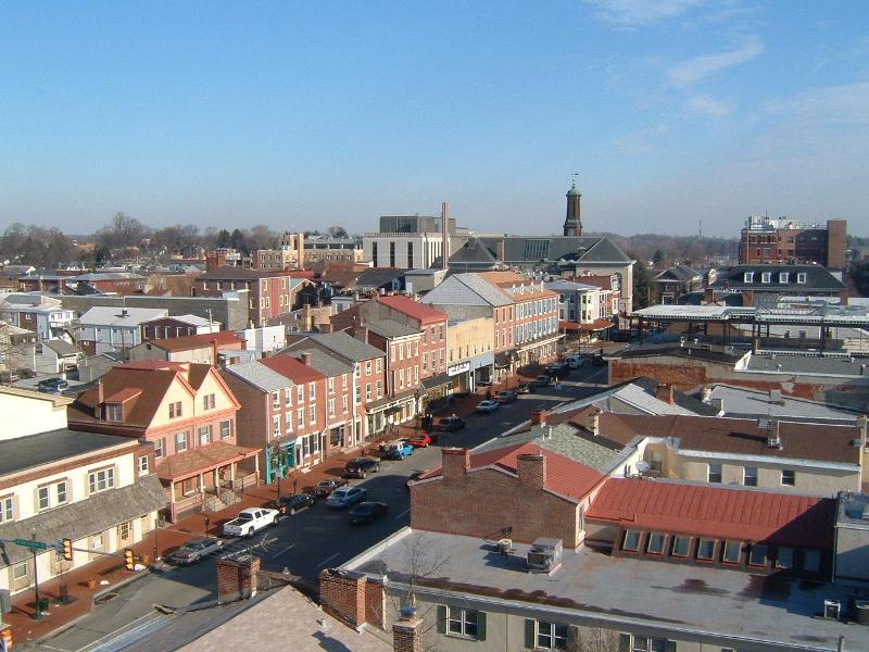 Historic brick storefronts line a downtown street under a clear blue sky.