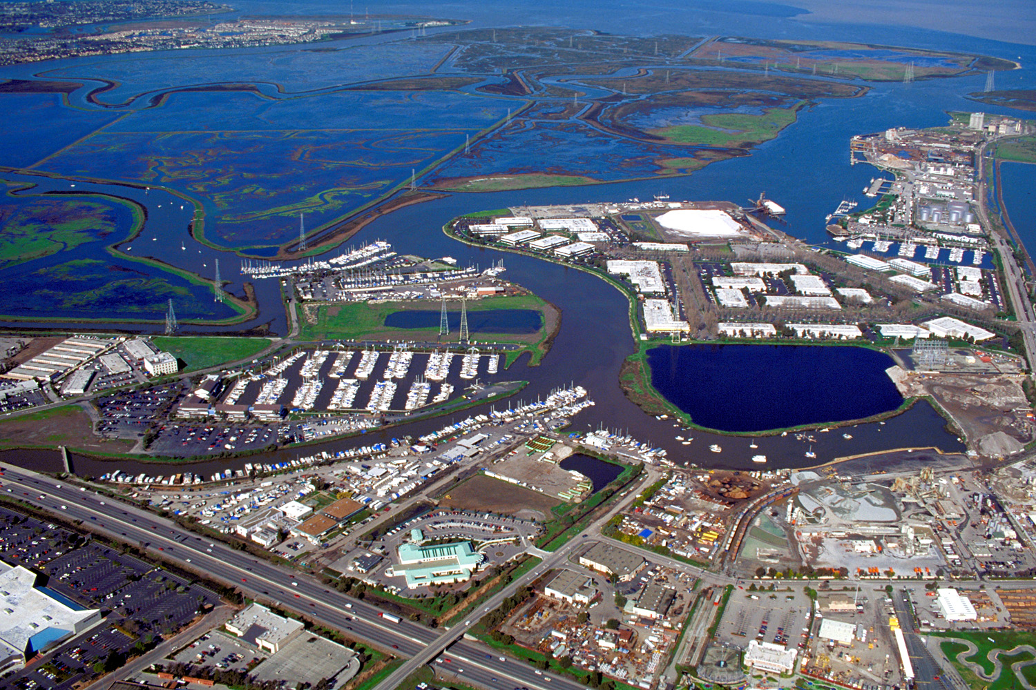 Aerial view of a port, marina, and wetlands along a bay waterway.
