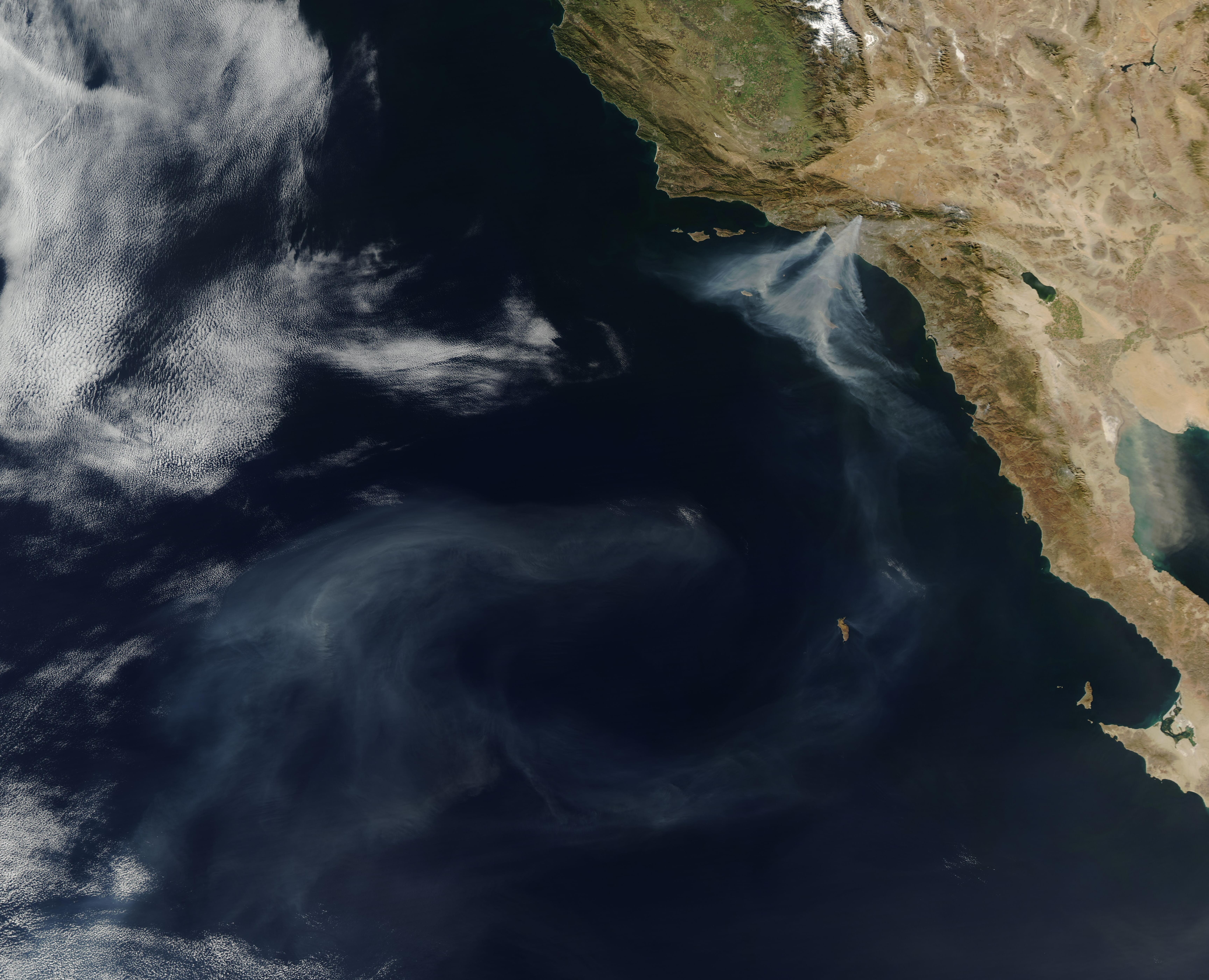 Satellite view of two thick smoke plumes from wildfires near Los Angeles drifting over the Pacific Ocean.