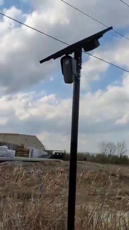 Solar-powered automatic license plate reader camera mounted on a metal pole outdoors.