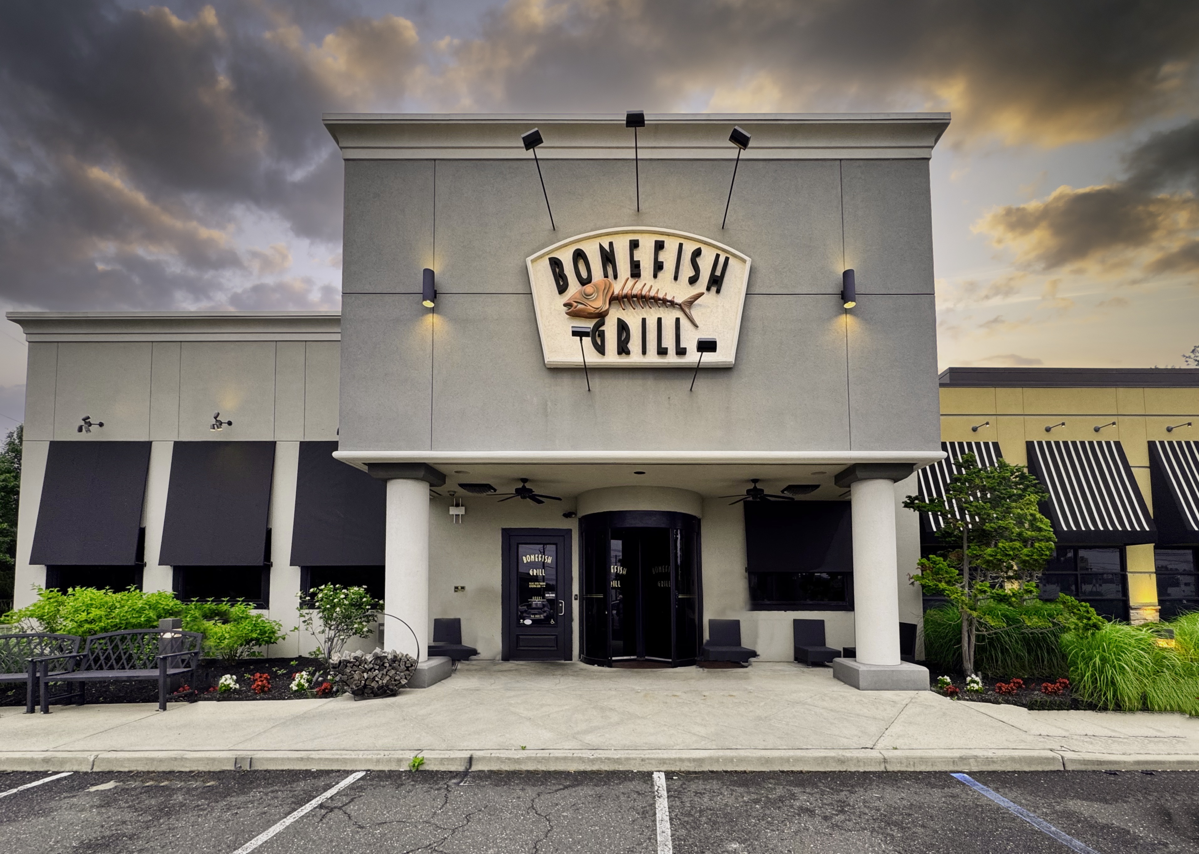 Exterior of a Bonefish Grill restaurant with signage, black awnings, and landscaping.