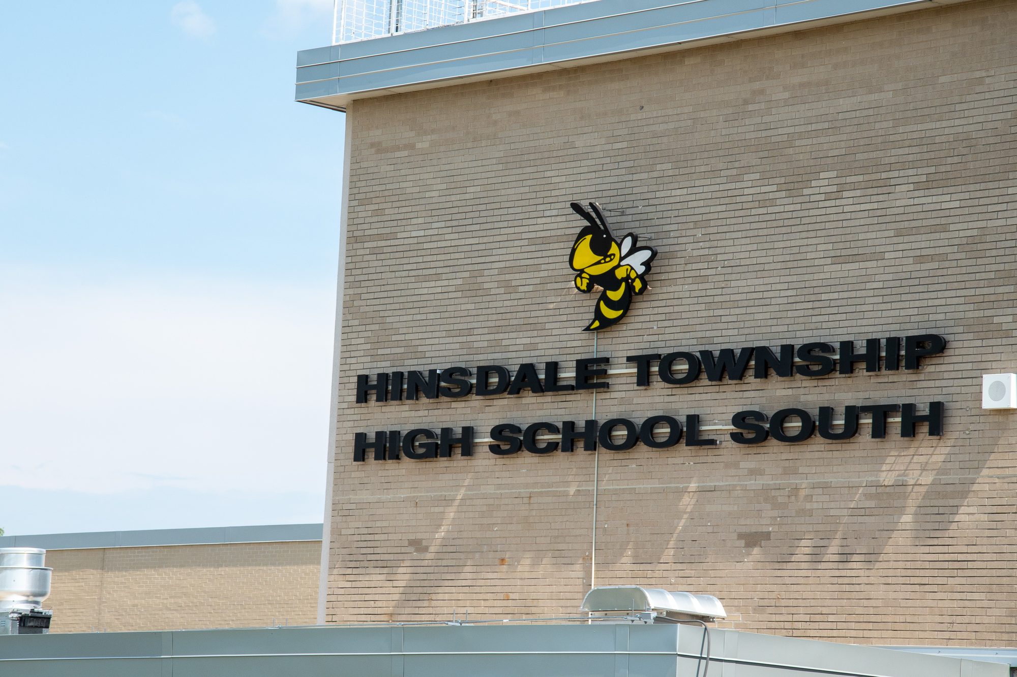Brick school building exterior with large name sign and hornet mascot logo.
