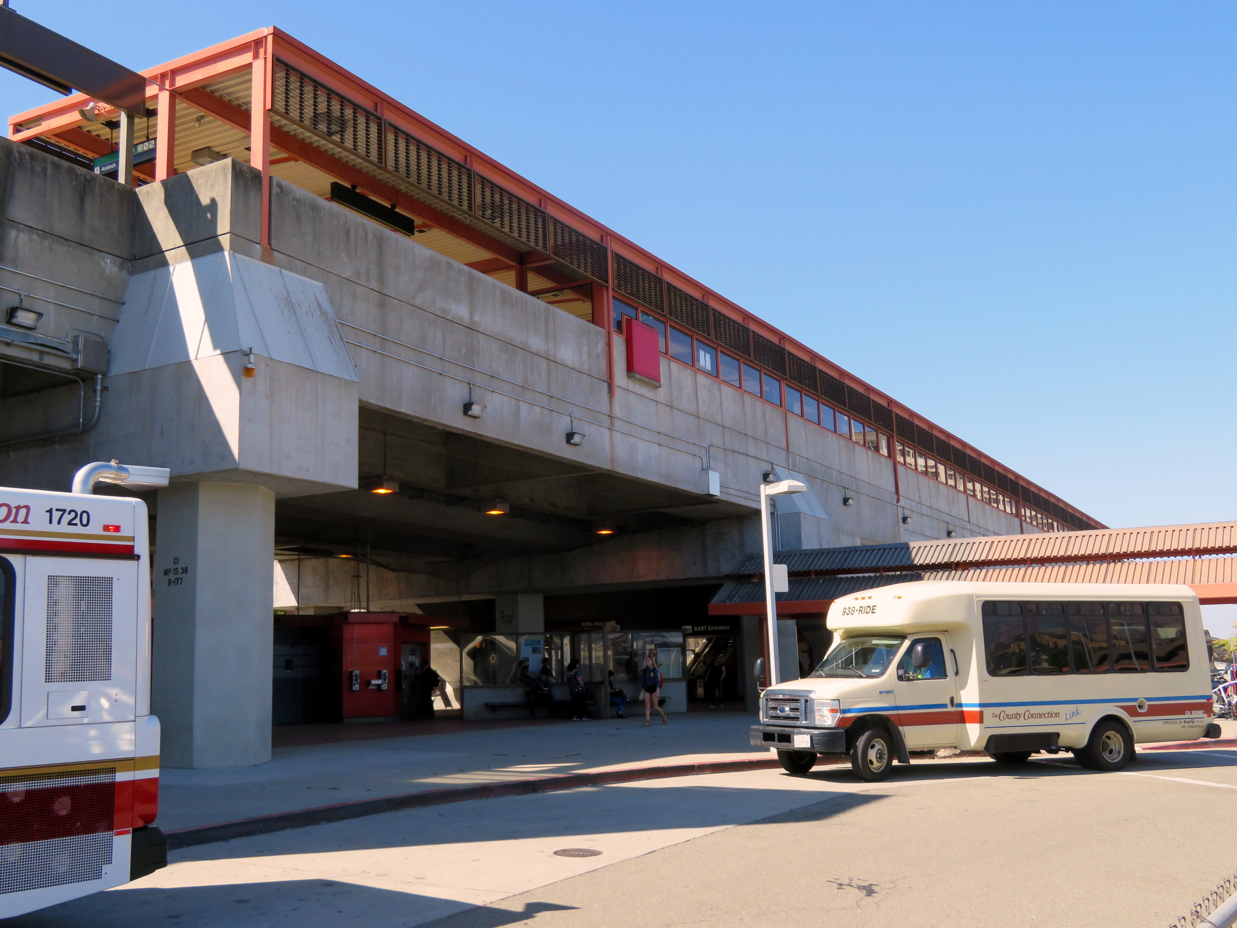 BART station exterior with buses parked outside under a blue sky.