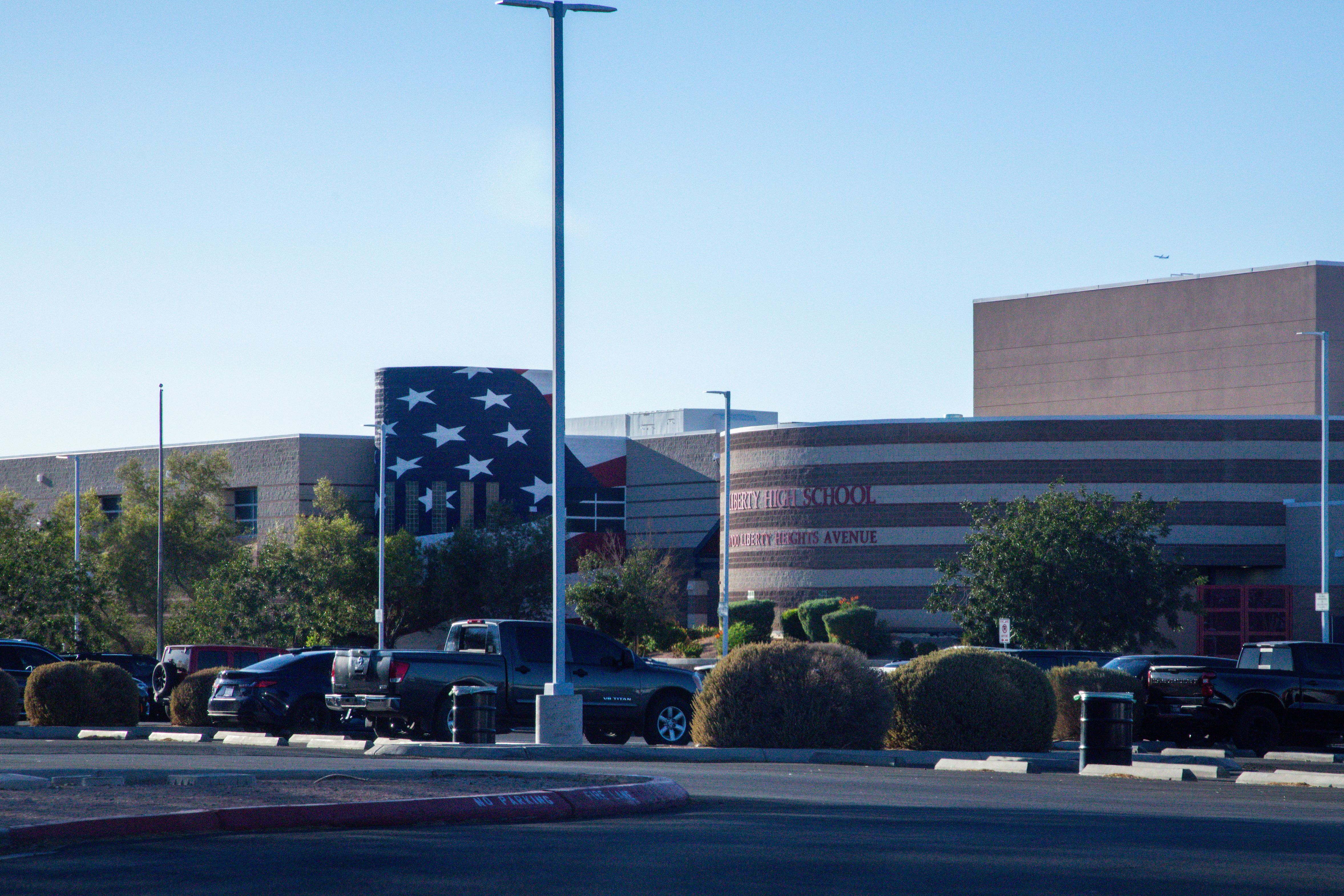 Front entrance and parking lot of a Henderson high school building with an American flag cylindrical structure.