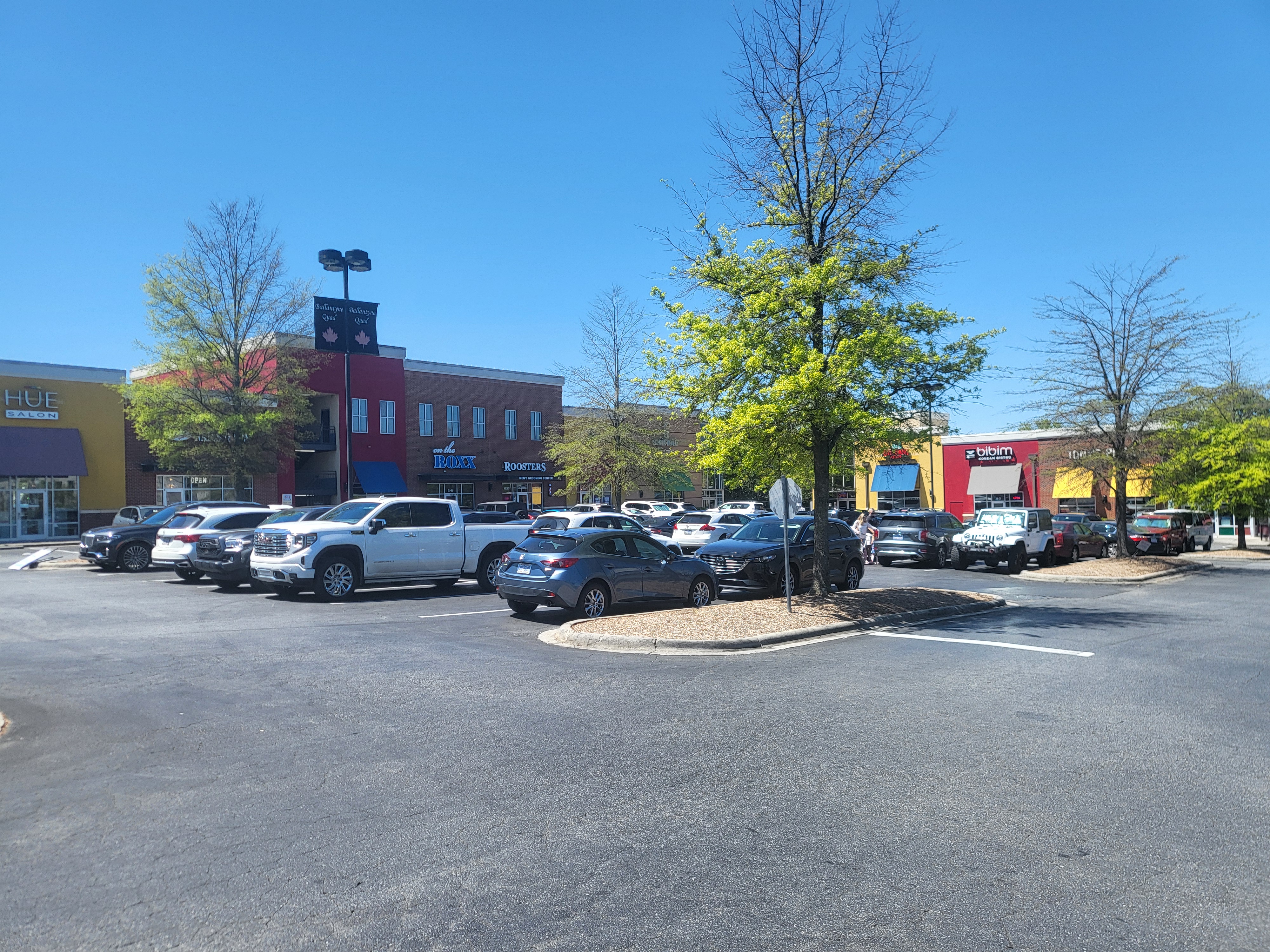 Storefronts and parking lot at a Ballantyne shopping center on a sunny day.