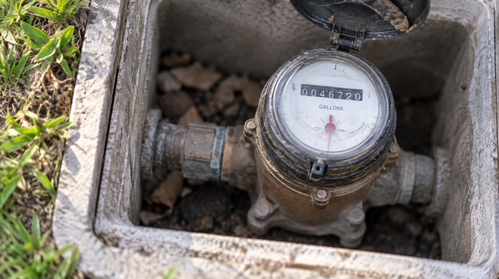 Close-up of a residential water meter dial set in a concrete curb box.