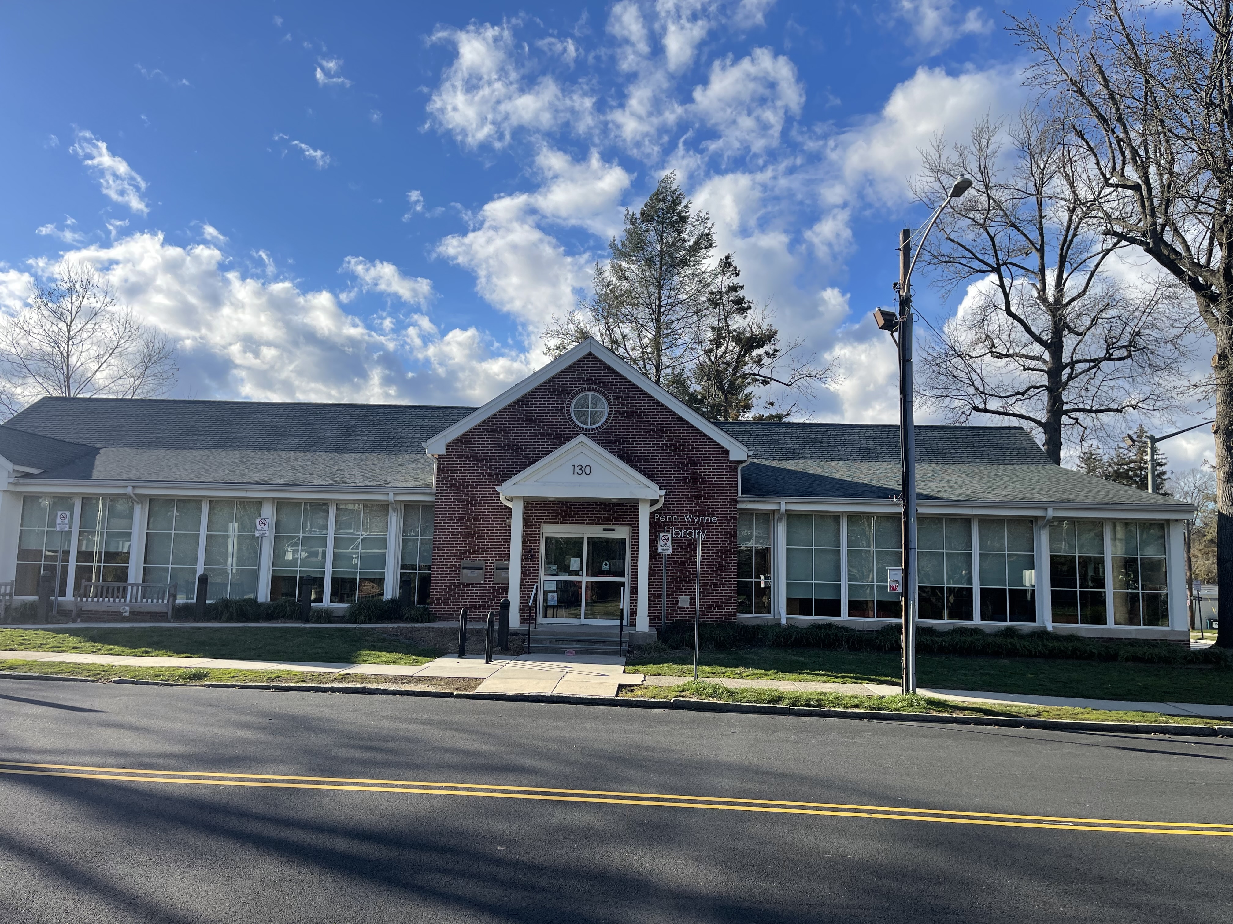 Single-story red brick library building with white columned entrance and large windows