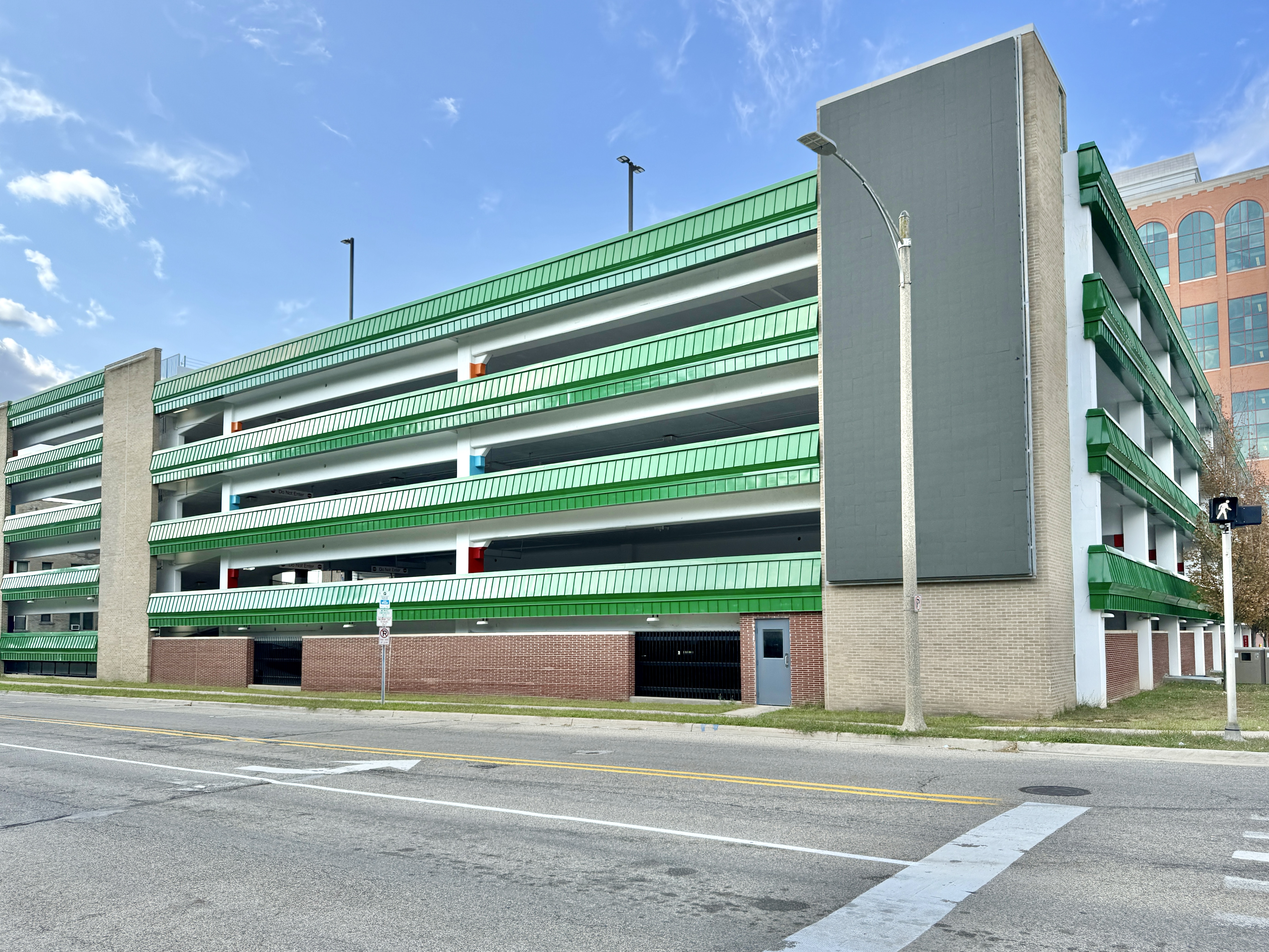 Multi-story parking garage with green metal railings at a downtown street corner.