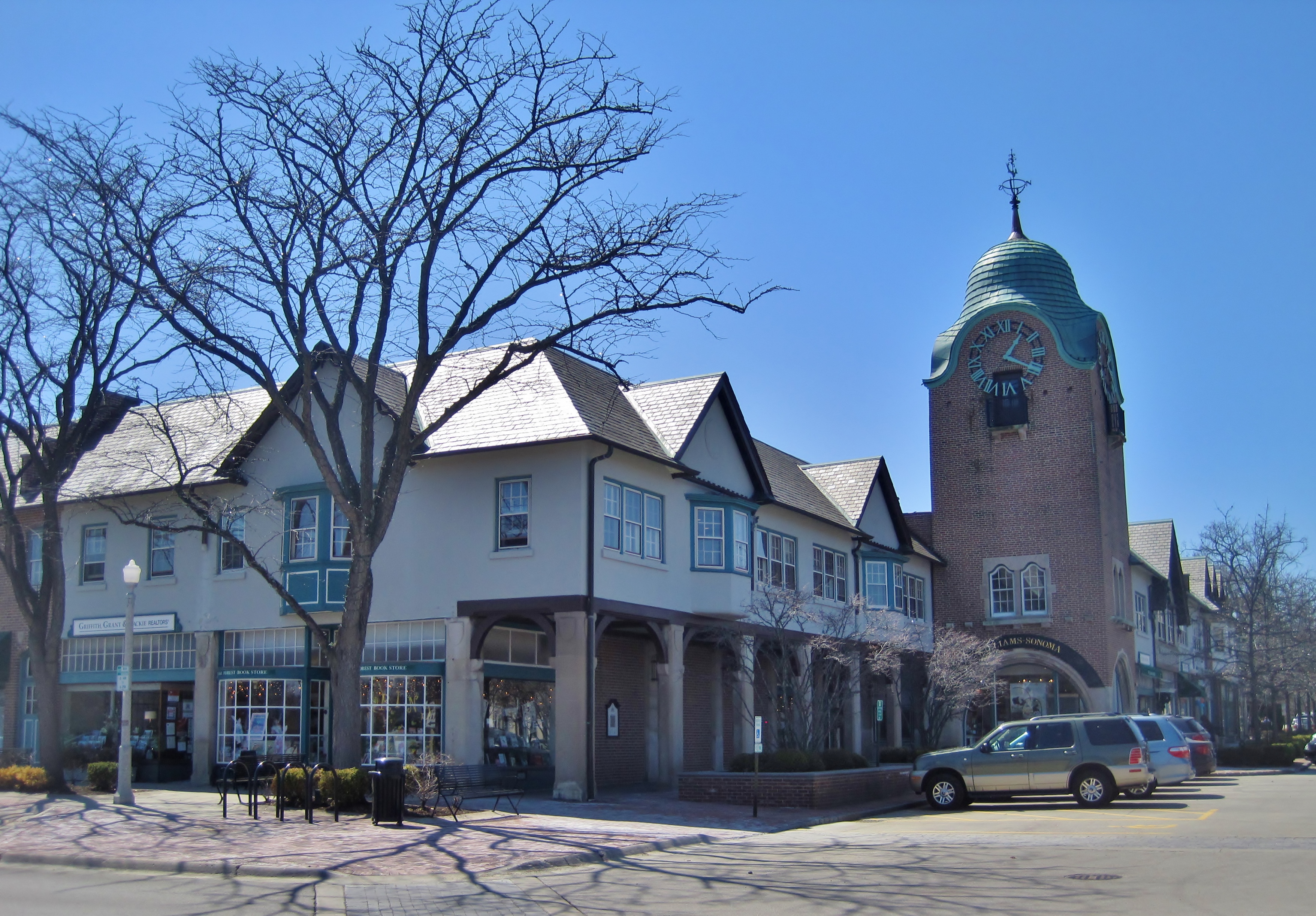 Tudor-style commercial buildings and a brick clock tower with a green dome at Market Square.