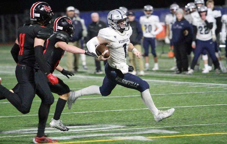 A Wilsonville High School football player in a white number 1 jersey running with the ball under stadium lights.