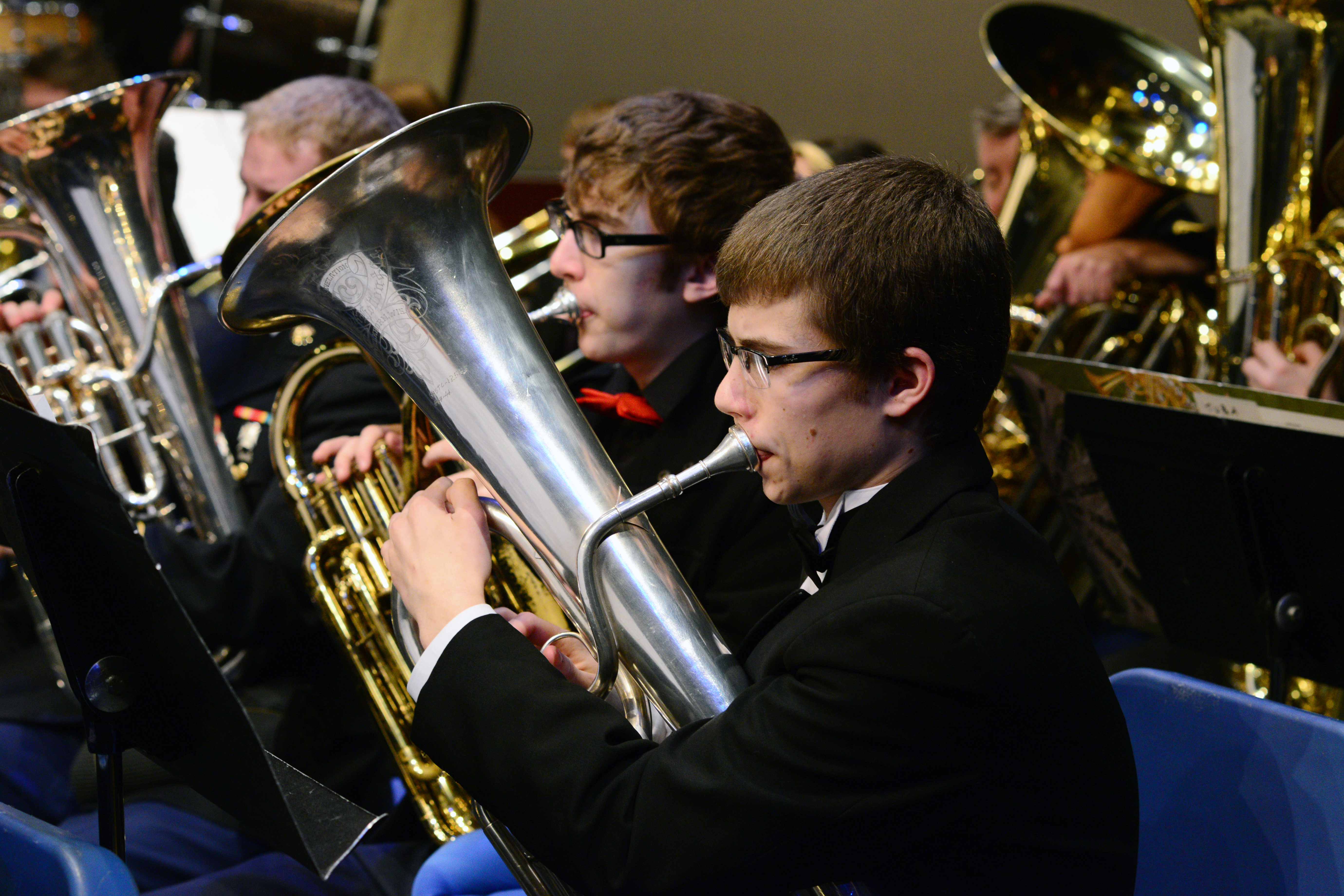 A student in black formal attire plays a silver euphonium in a band concert.
