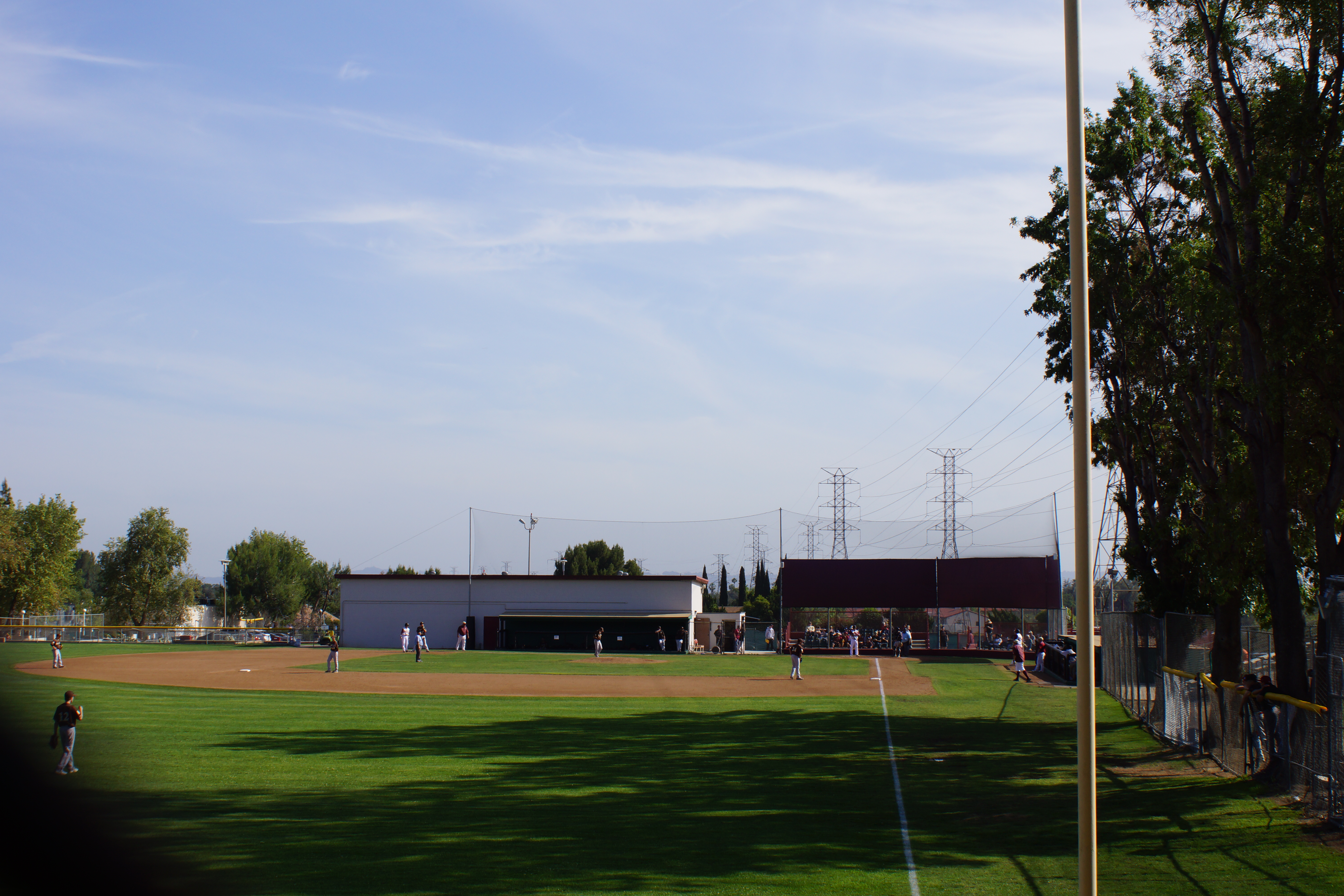 Players spread across a grass softball diamond during a high school game.