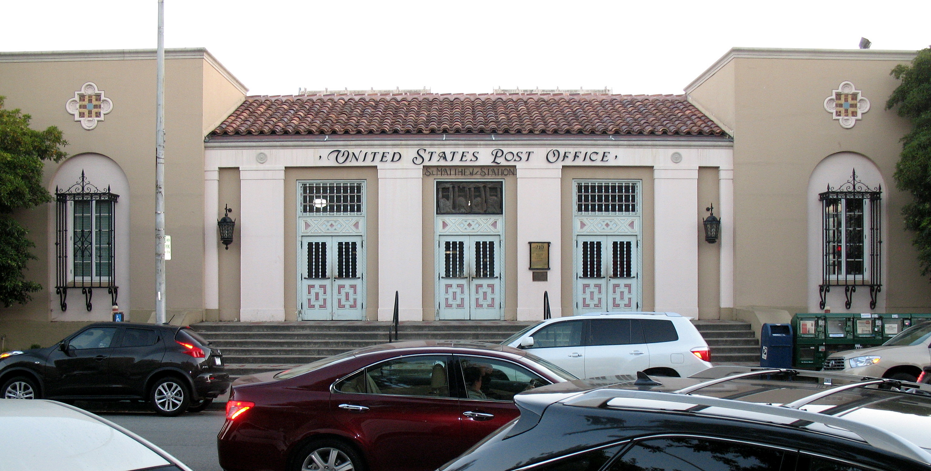Spanish Colonial Revival post office building with red tile roof and arched entryway.